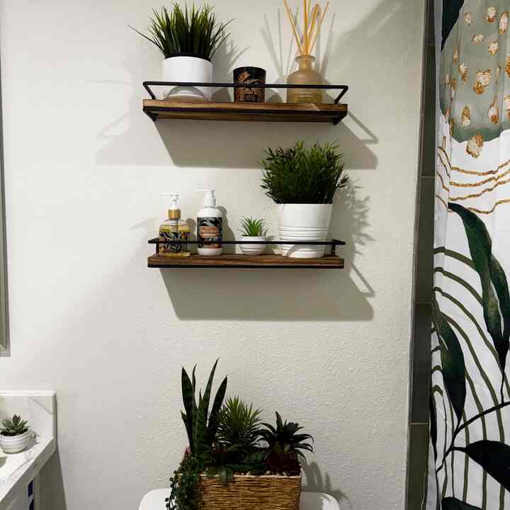 White-walled bathroom with wood tone floating shelves featuring plants and diffuser, creating a natural atmosphere