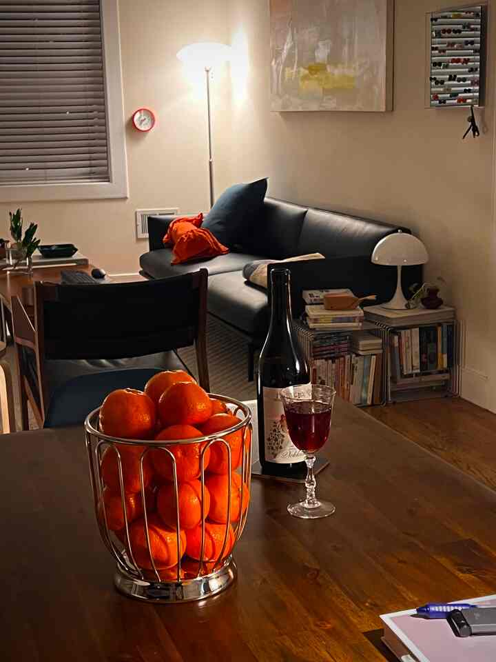 Natural color and black toned living and dining room featuring sofa and dining table with wine glass, creating a cozy home bar atmosphere