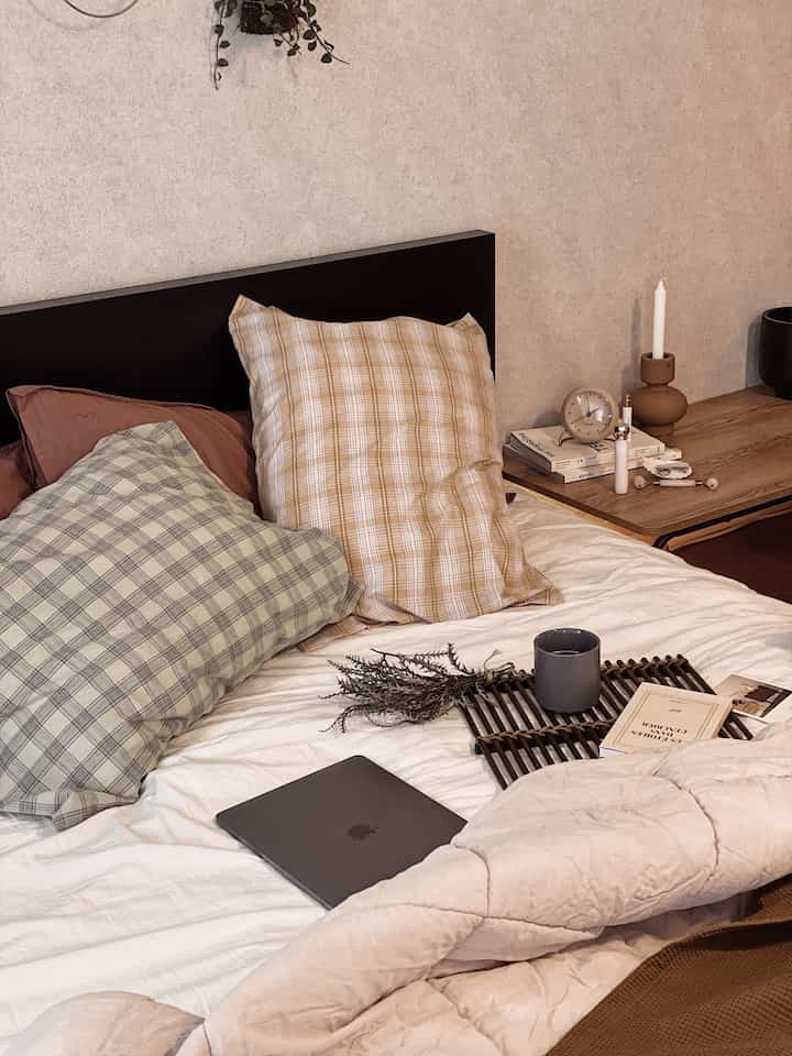 Bedroom in brown and white tones featuring a bed, nightstand with clock, with a natural cozy atmosphere
