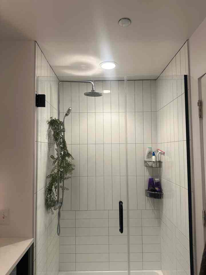 Modern bathroom shower booth with white tiles and glass door