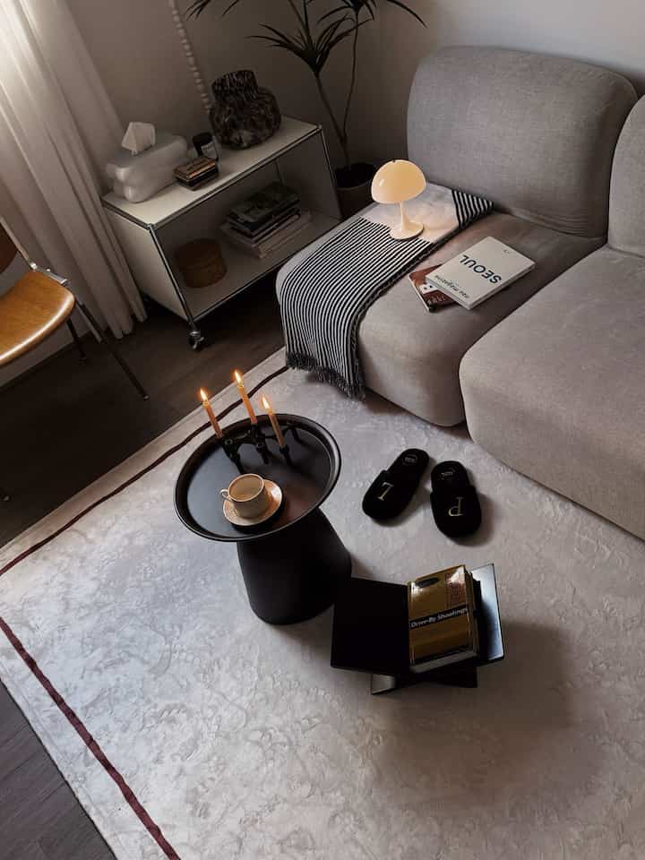 Modern cozy living room featuring gray sofa and black coffee table with candles and teacup