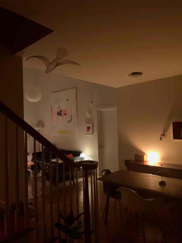 Warm brown wood tones and white walls define a cozy living and dining room featuring modern furniture and soft lighting at night