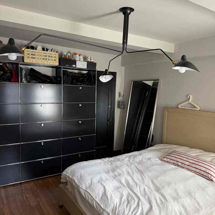 Natural modern tone bedroom featuring a large beige bed with white bedding, and black storage cabinets neatly arranged on the left