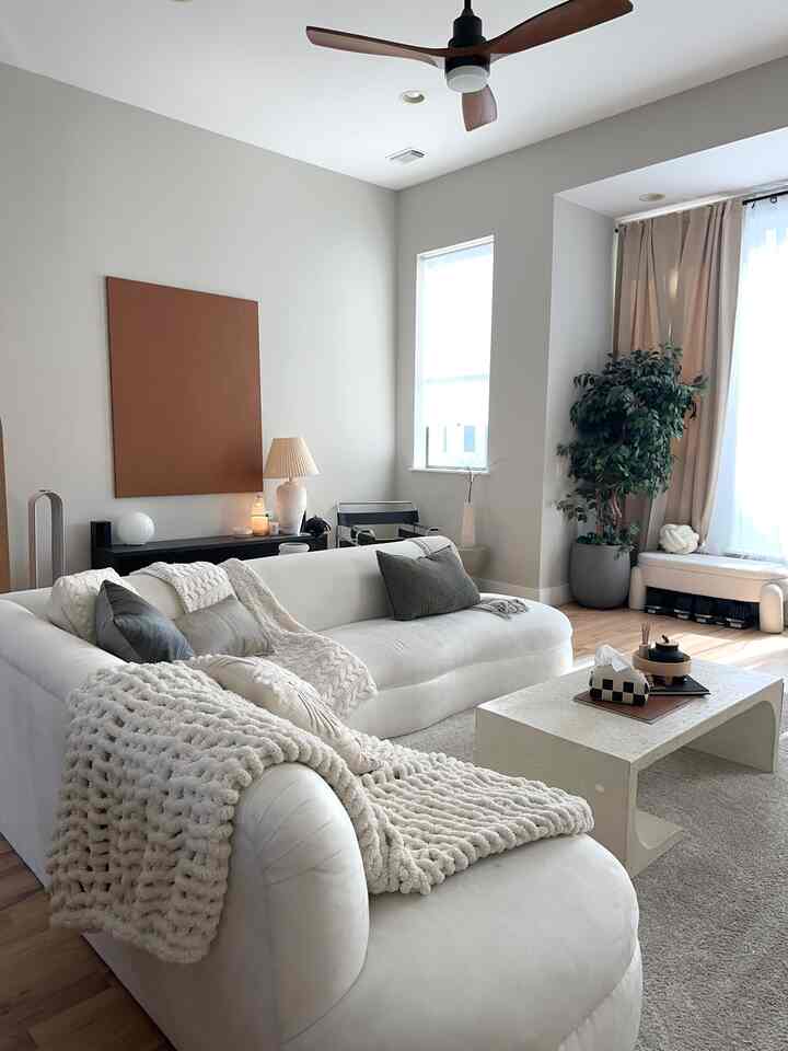 Natural tone living room featuring a white sofa with chunky throw blankets and cushions creating a cozy atmosphere