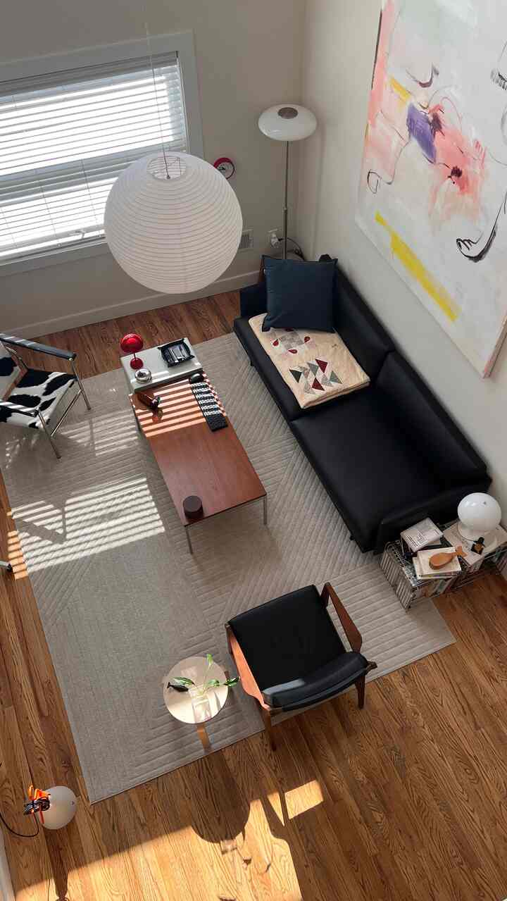 White-walled living room with wood-toned floor featuring modern sofa, armchair, coffee table, and lighting creating a clean atmosphere