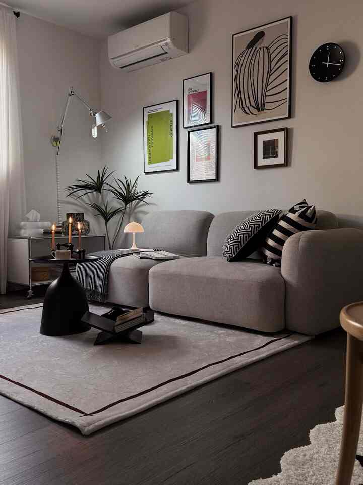 Gray-toned living room featuring a large sofa and multiple posters on the wall in a modern setting