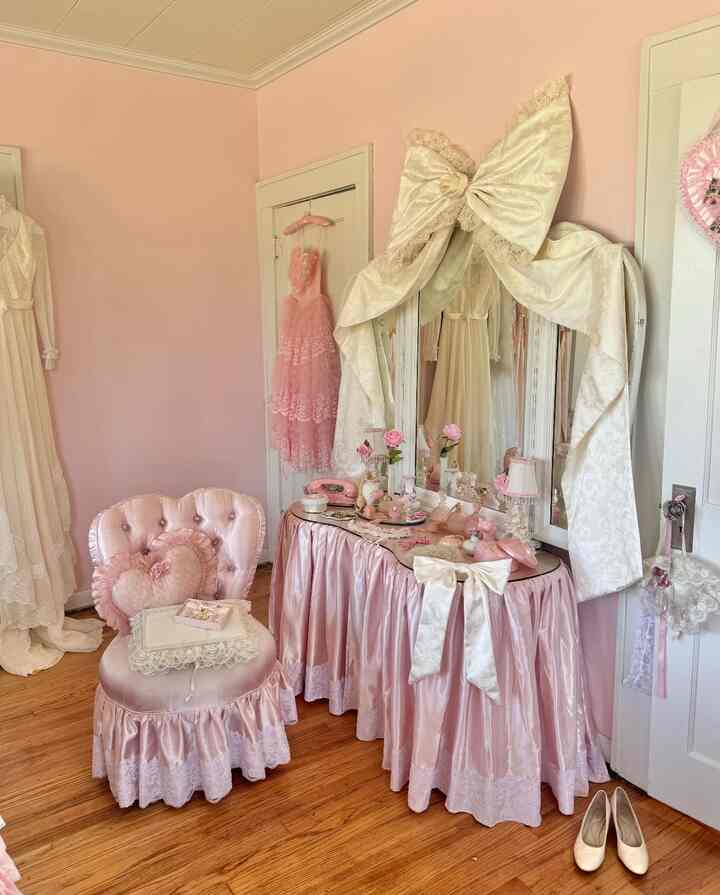 Pink-toned bedroom featuring a satin skirted vanity and vintage style chair with romantic shabby chic atmosphere
