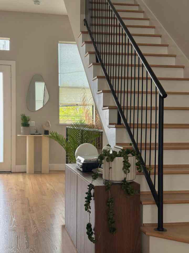 Natural wood tones and staircase in a clean entrance space, green plants add a natural warm atmosphere
