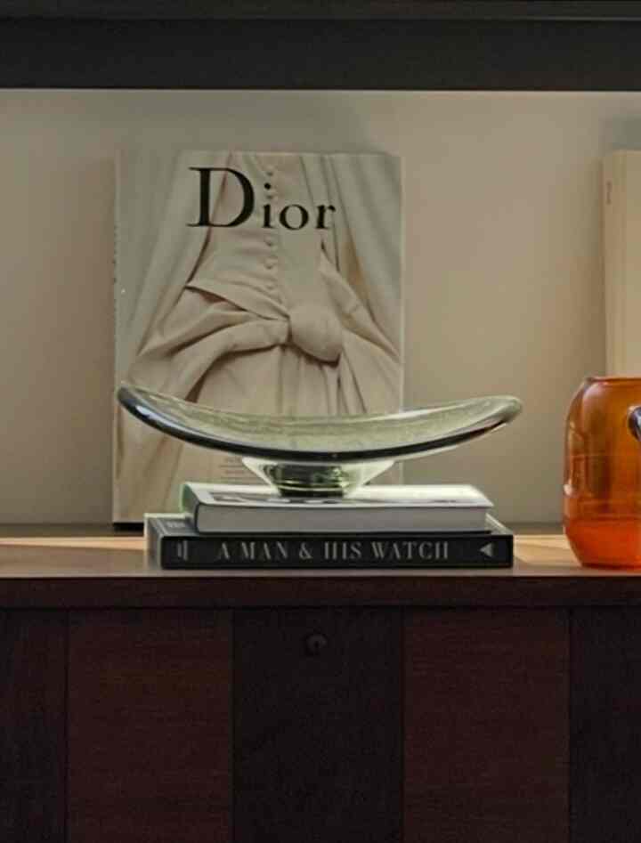 Natural-toned living space featuring a wooden coffee table topped with a vintage art glass bowl and luxury coffee table books, creating a sophisticated interior