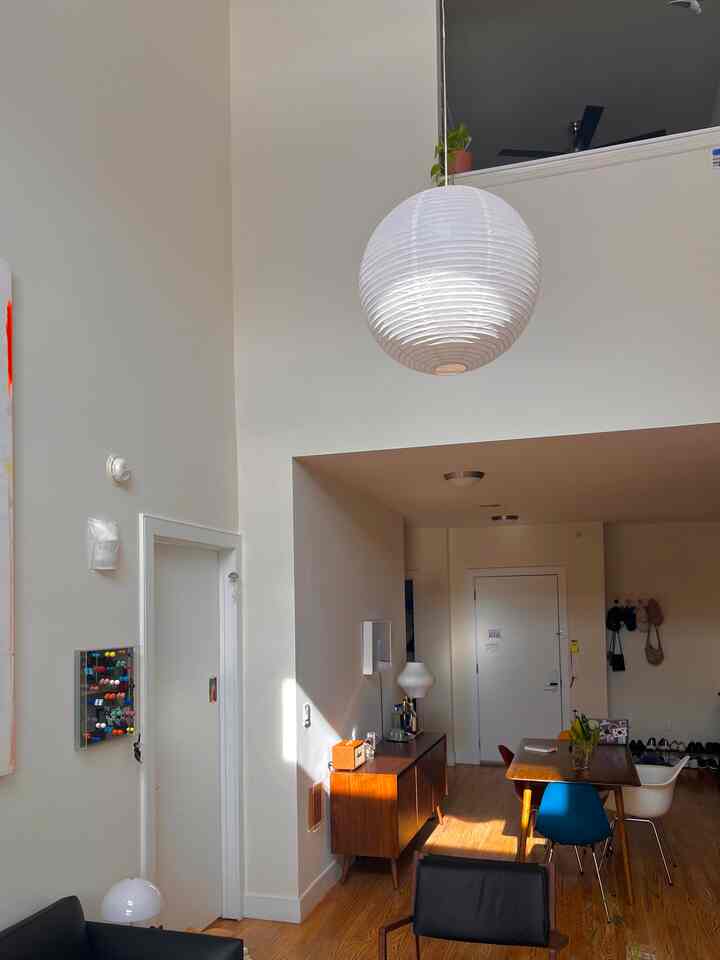 Modern two-person living and dining space featuring white walls, wood tones, pendant lamp, and warm natural light