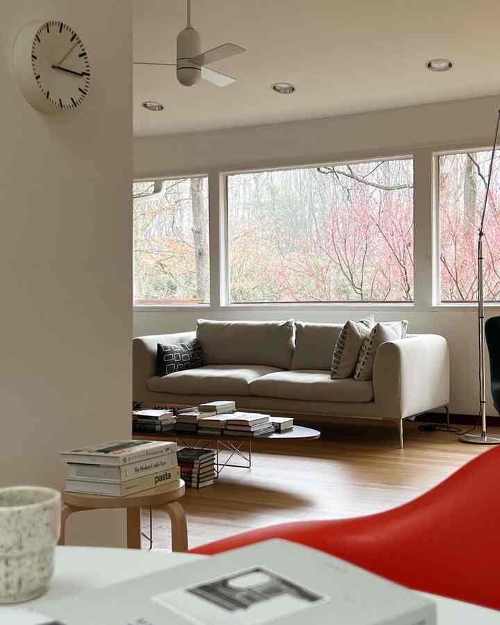 White and red toned living room featuring beige sofa, red armchair, books and tables in a minimalist setting
