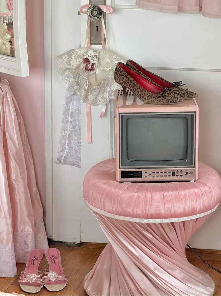 Pink-toned bedroom featuring a vintage pink Zenith TV on a pink upholstered stool, creating a cozy vintage atmosphere