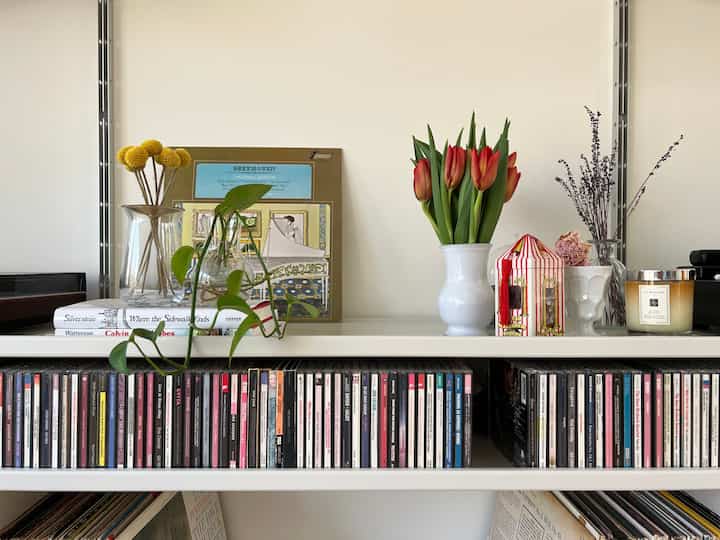 Mid-Century Modern living room with white walls and shelving, decorated with vases and candles in a tidy setting