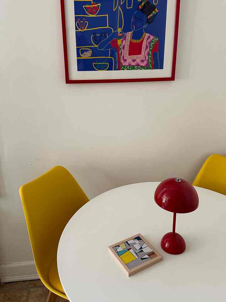 Modern dining room with white walls, yellow dining chairs and a red table lamp creating a vibrant atmosphere