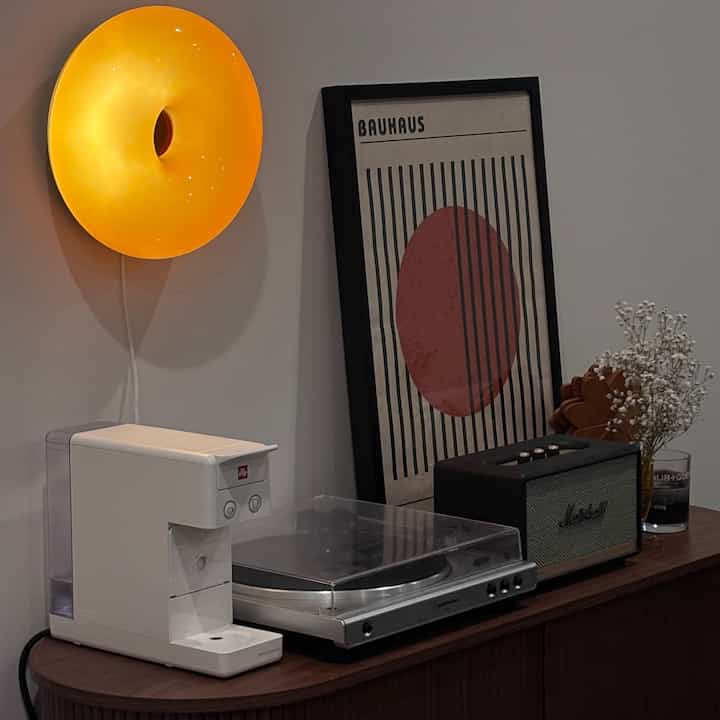 Brown wood-tone sideboard topped with white coffee machine and Marshall speaker in a mid-century modern style dining room