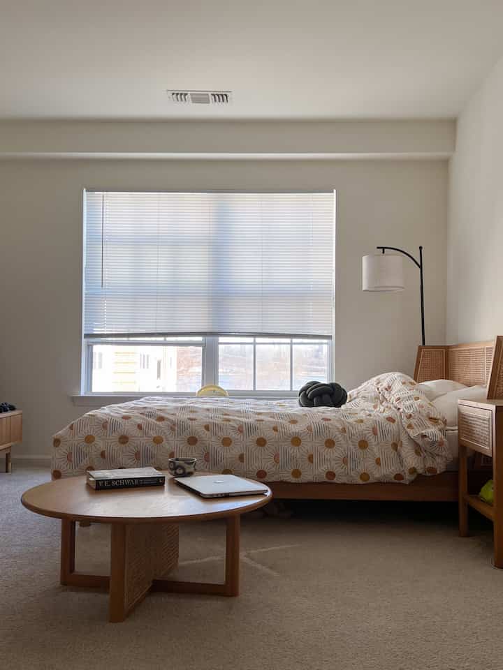 Natural wood tone and beige bedroom with sunlit window and patterned duvet cover creating a warm atmosphere