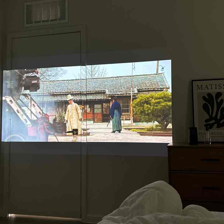 White and brown toned bedroom with a cozy atmosphere featuring a movie projected on the wall