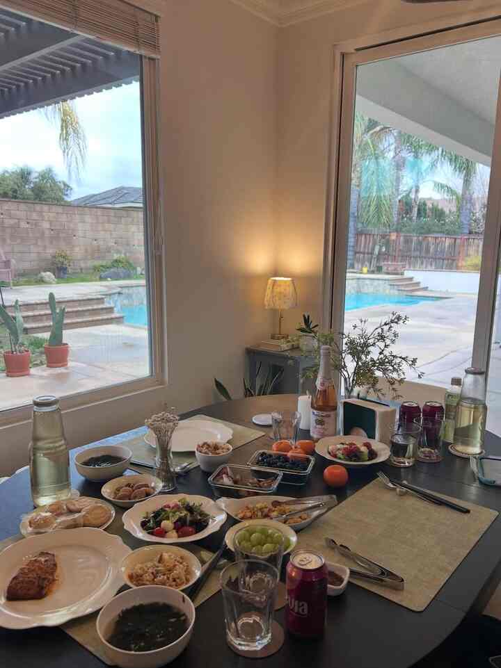 Bright white-walled dining room with black dining table featuring various dishes and drinks, creating a home party atmosphere