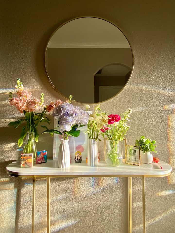 Natural color toned entrance featuring a console table with various vases and flowers in a cozy setting