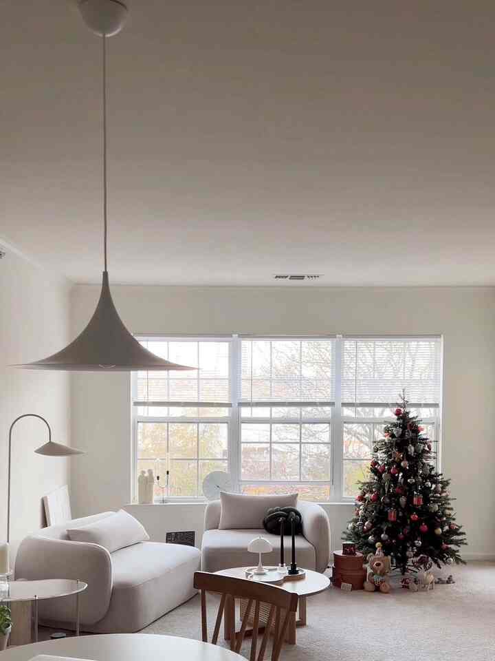 White-toned living room featuring sofa and decorated Christmas tree with a clean, minimal atmosphere