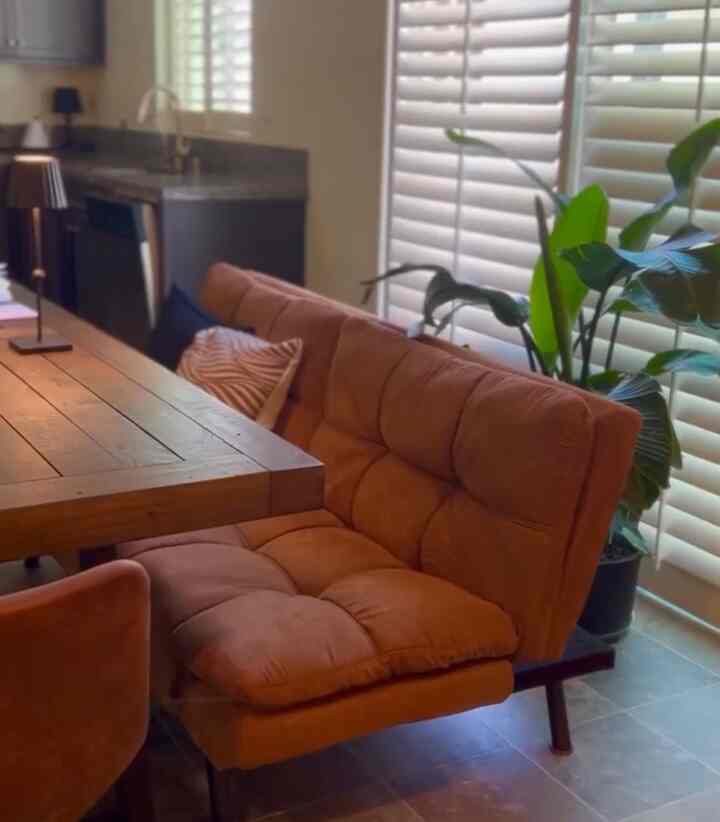 Warm brown and wood-tone dining room featuring a sofa placed beside the dining table, creating a cozy cafe-style atmosphere