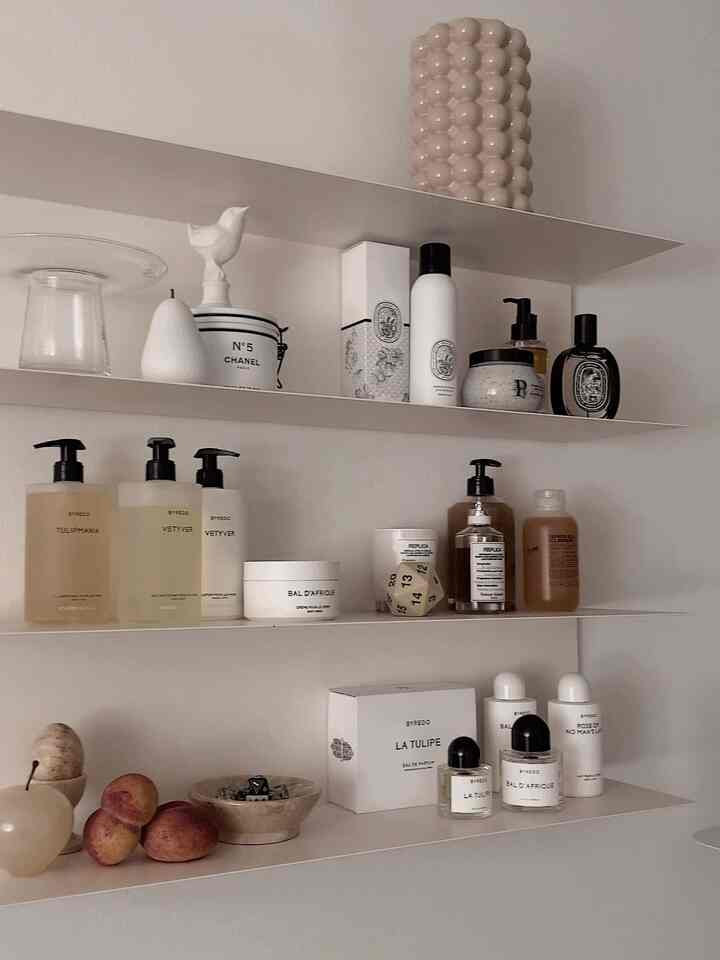 White and brown toned shelf space featuring fragrances and candles in a tidy minimal modern interior