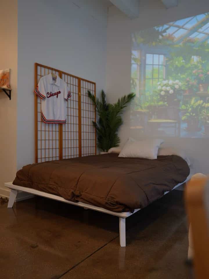 Studio bedroom featuring a white low-profile bed frame with brown bedding, cozy and minimal Japandi style interior