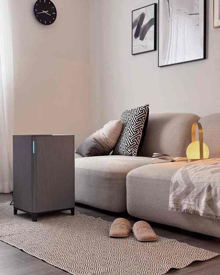 Beige and modern toned living room featuring a simple sofa with patterned cushions and warm lighting creating a cozy atmosphere