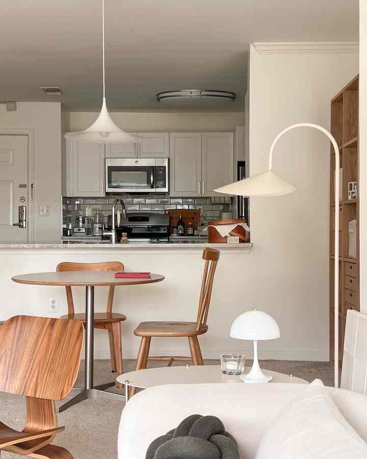 Natural-tone living room connected to kitchen featuring wooden dining table and chairs, pendant light creating cozy atmosphere