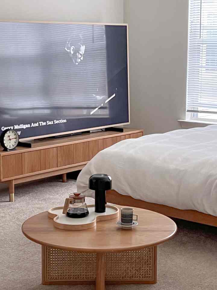 Wood tone and white bedroom featuring wooden furniture, coffee table, and black accent pieces in a cozy space