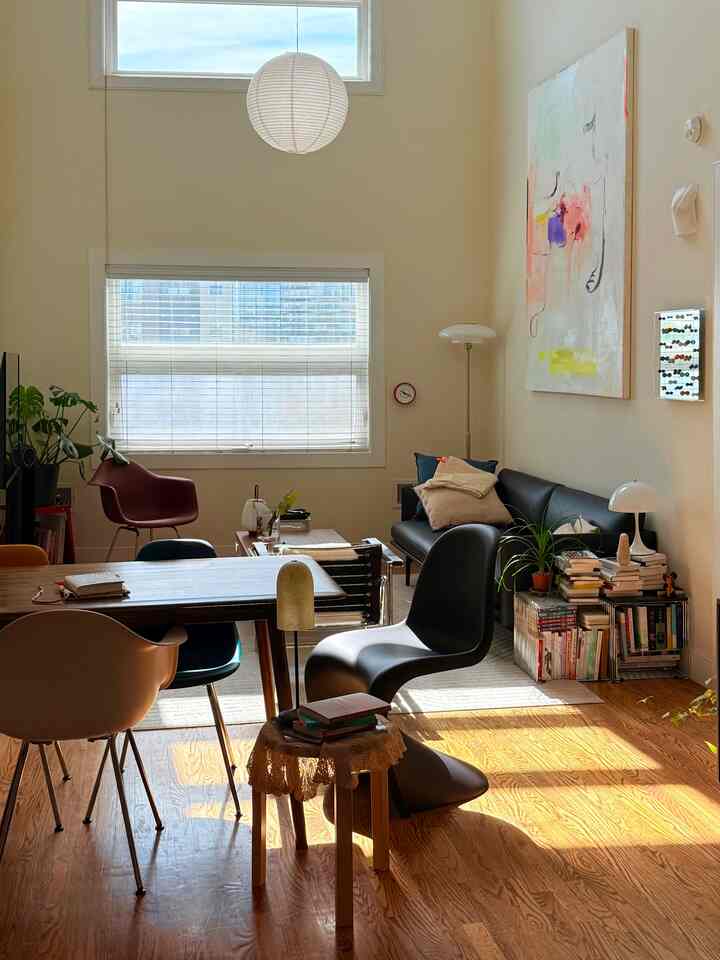 Warm wood-tone floor and white walls in a living room featuring a dining table and assorted chairs in a simple natural setting