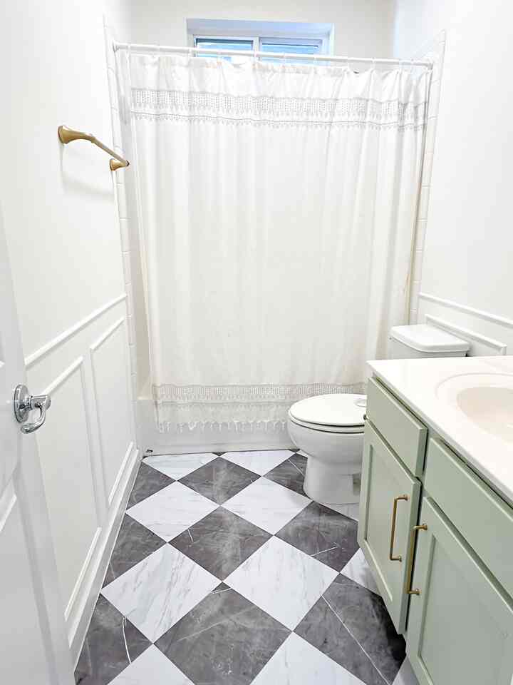 White and gray toned bathroom featuring a shower curtain, toilet, and vanity cabinet in a simple setting