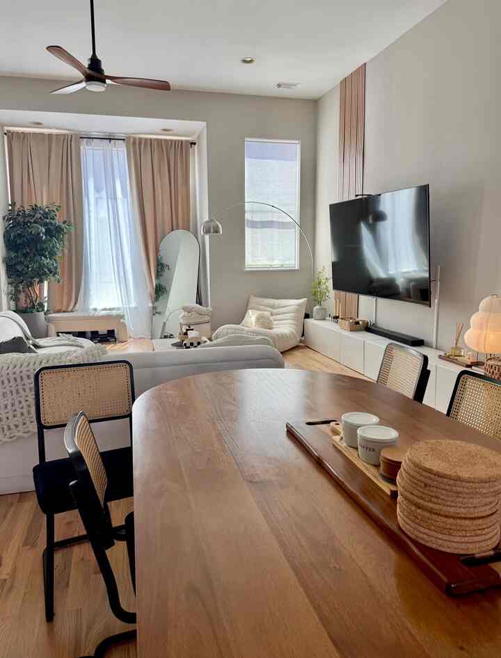 White walls and wood tone furniture define a Mid-Century Modern dining and living room with a warm, natural atmosphere