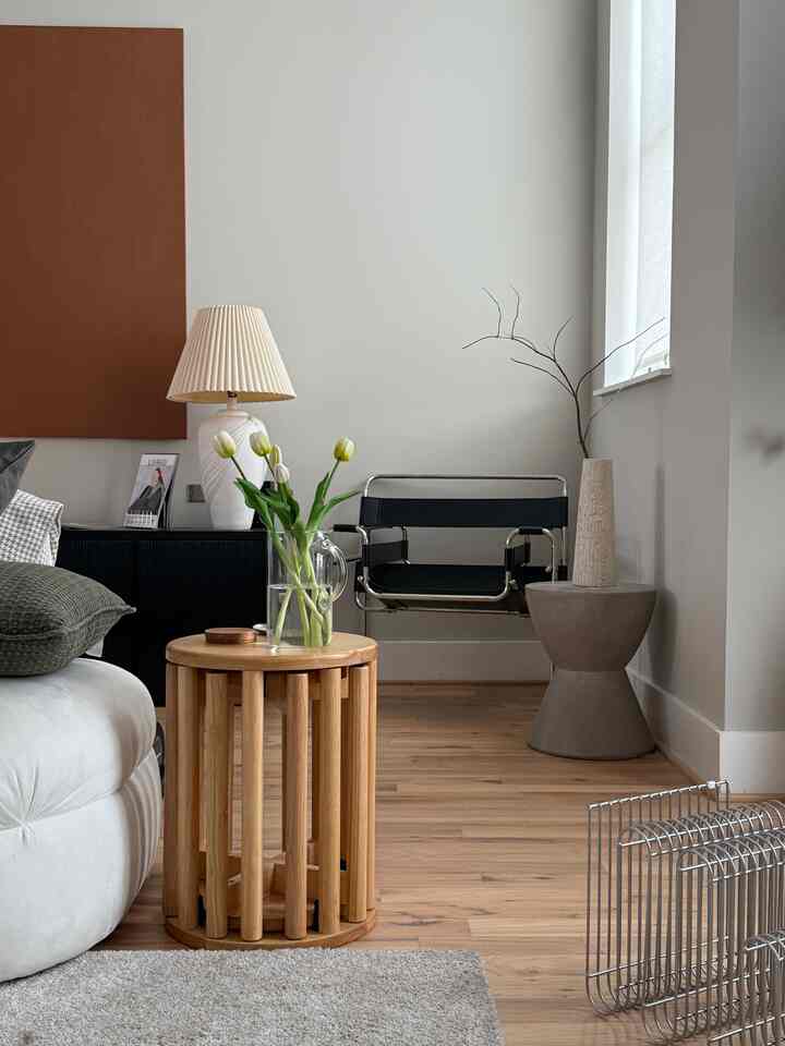 Soft natural tone living room featuring wooden side table and black armchair creating a warm atmosphere