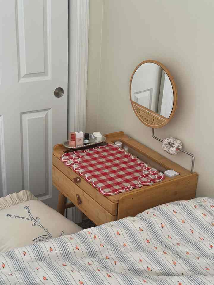 Natural-toned small bedroom with beige walls, wooden vanity desk, and floral fabrics creating a cozy atmosphere