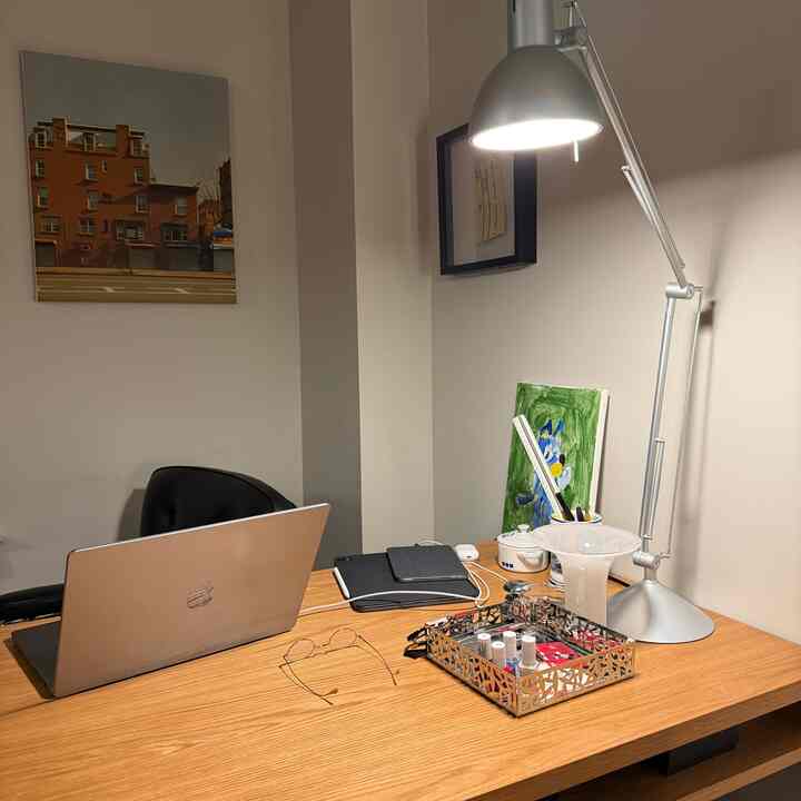 Brown wood-tone desk with silver table lamp in a simple, modern home office space
