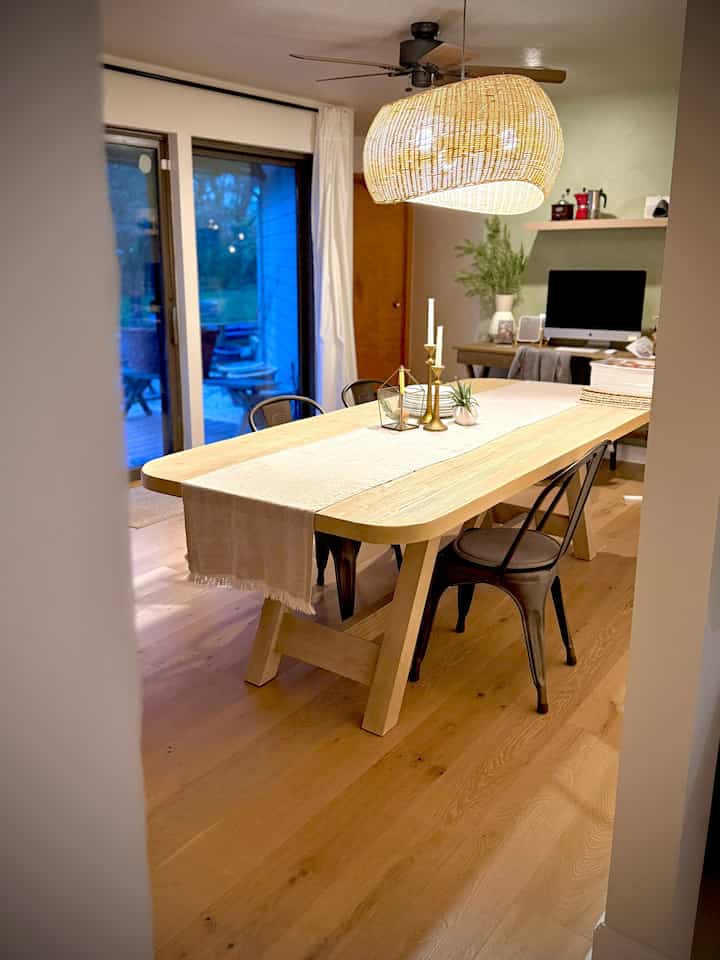 Natural wood tone dining room featuring a large wooden dining table and wicker pendant light creating a cozy atmosphere
