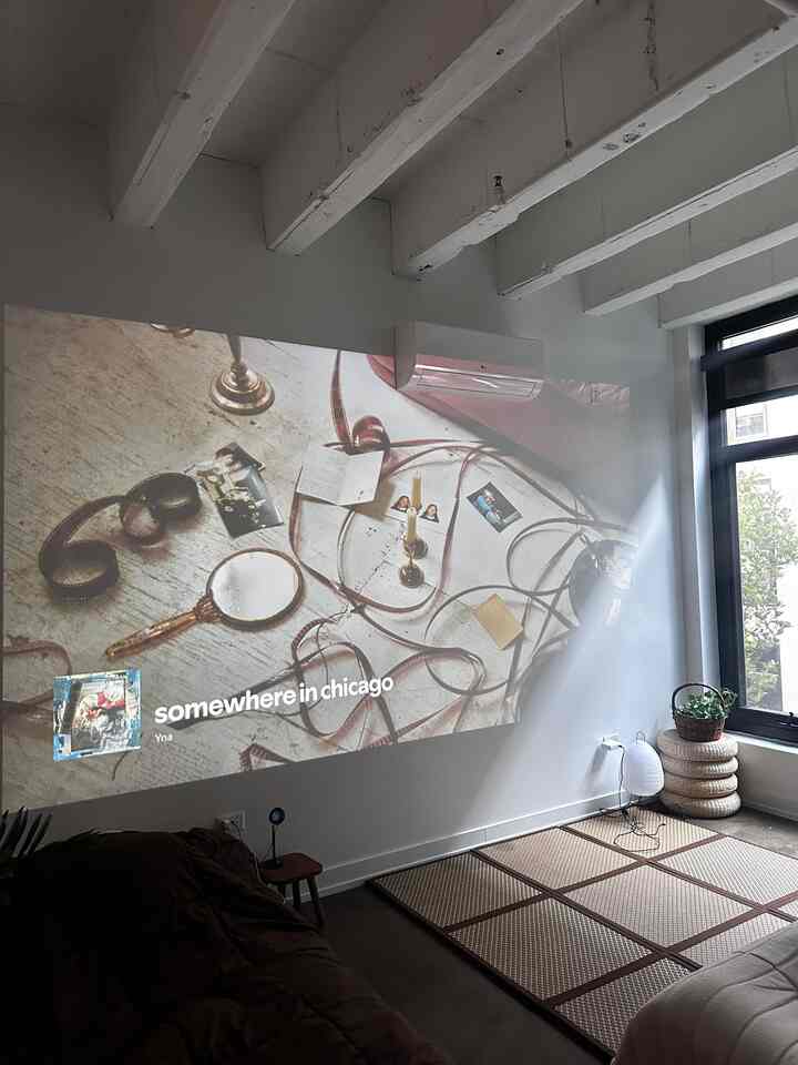 Light gray toned living room featuring Japanese tatami mats, minimal sofa, and a projector casting images on the wall