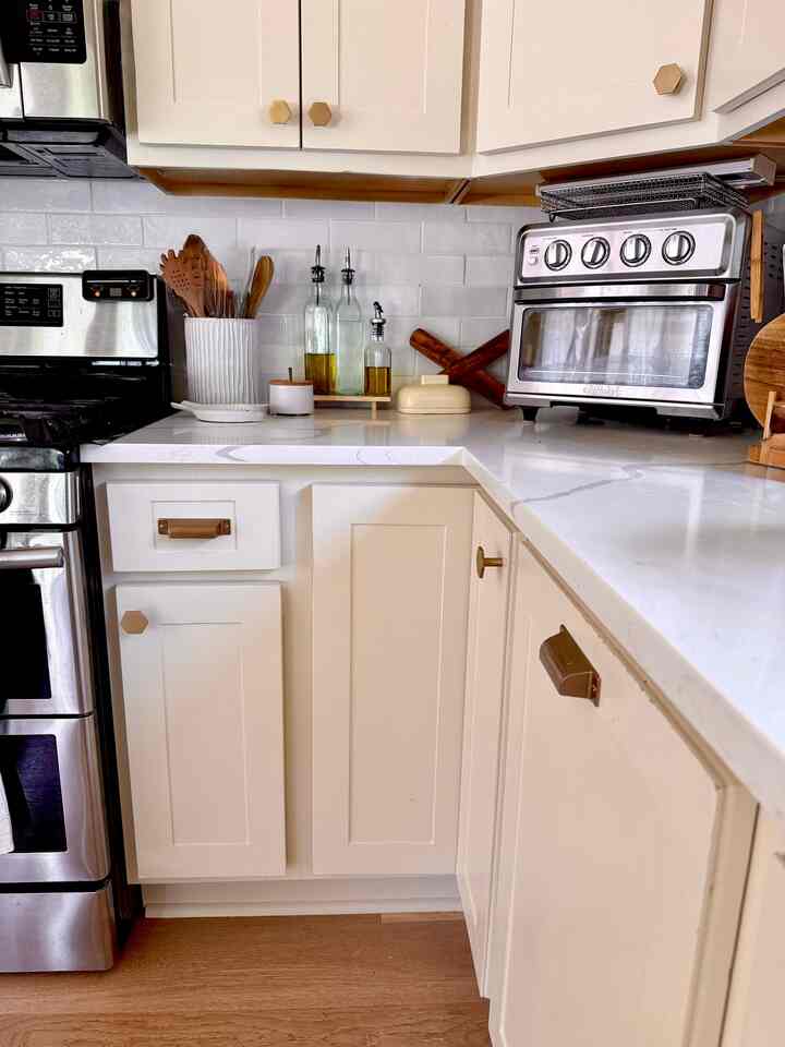 Modern kitchen in creamy white and brown tones featuring stainless steel appliances and wooden utensils with a warm atmosphere