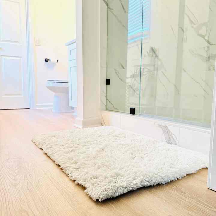Bright white and beige-tone bathroom featuring a central fluffy bath mat, creating a cozy atmosphere