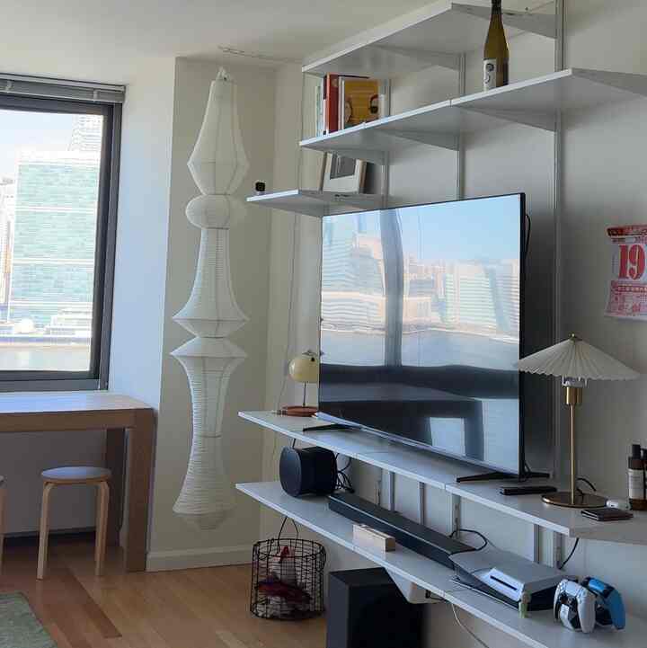 White walls and wood tone floor defining a compact home office and game room featuring TV and shelving