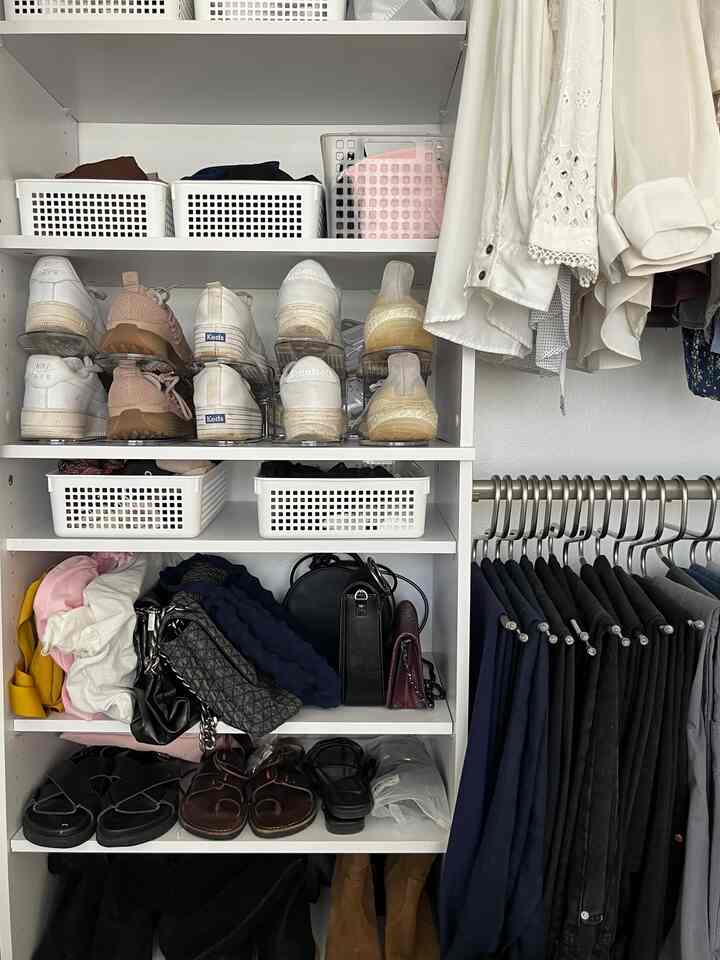White and black toned closet featuring organized shoe stackers and hanging clothes in a compact space