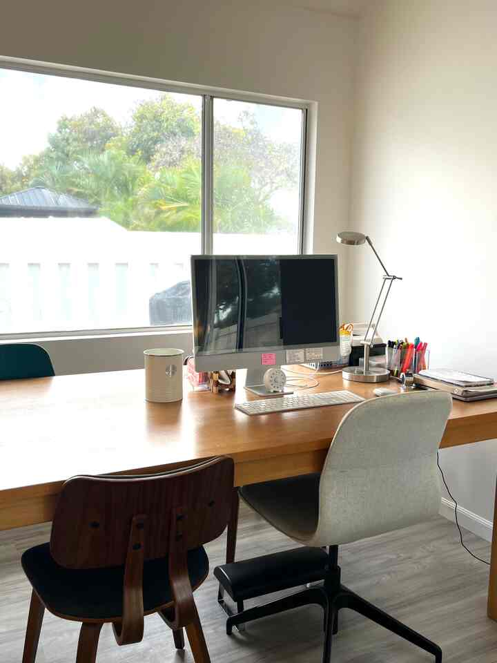 Natural-toned home office featuring large wooden desk with monitor and office chair in cozy workspace