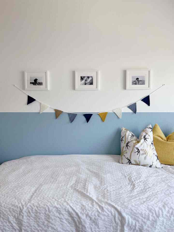 Blue and white toned kids' room featuring a white bed with cushions and family photos on the wall, creating a cozy atmosphere