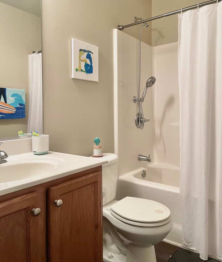 White and brown toned bathroom featuring shower curtain, toilet, and sink in a clean, functional space