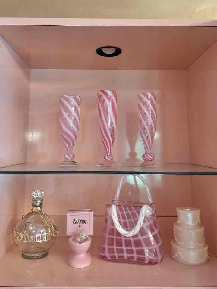 Pink-toned dining room hutch featuring vintage glass vases and decorative objets arranged neatly