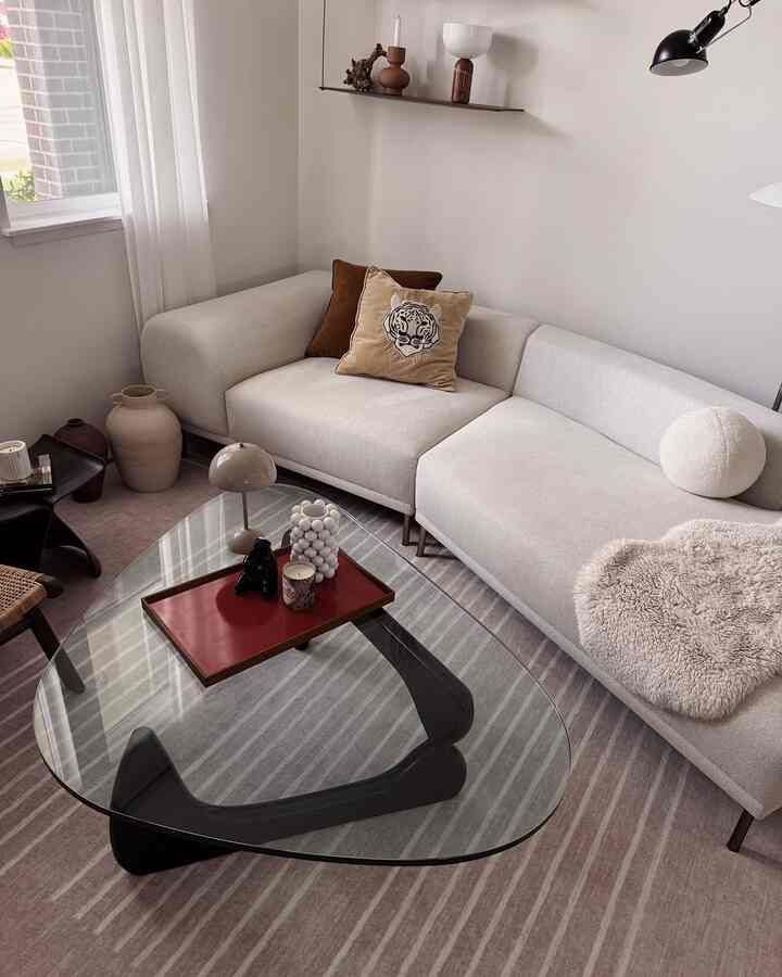 Natural color toned living room featuring beige sofa and glass coffee table with a calm and cozy atmosphere