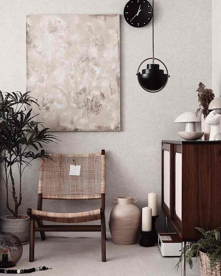 Natural-toned bedroom corner featuring wood furniture, rattan chair, plants, and pendant lighting creating a cozy atmosphere