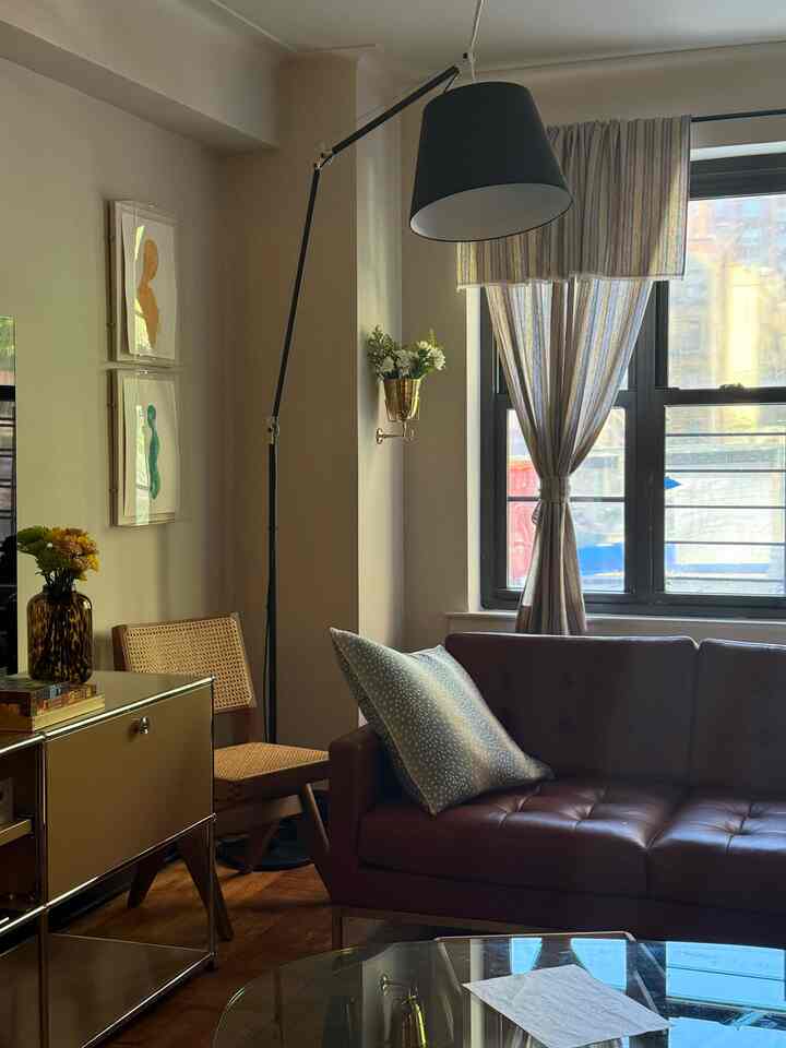 White-toned living room featuring brown leather sofa and wooden chair with a modern atmosphere