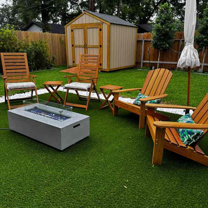 Backyard space with green artificial grass and wooden outdoor chairs, creating a cozy relaxation atmosphere